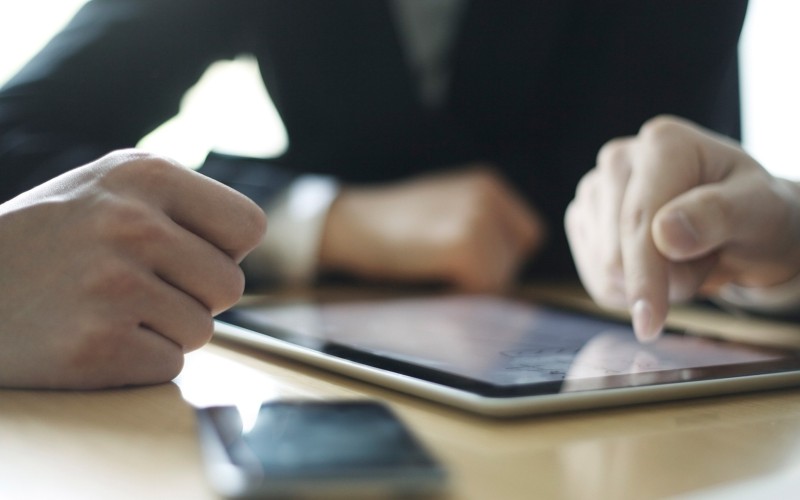 Trio sat at table with devices on desk