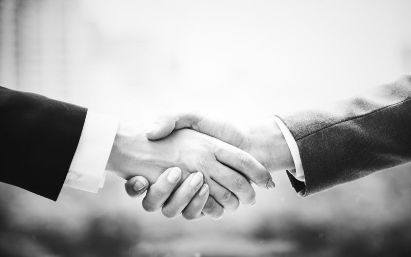 Greyscale image of two adults shaking hands